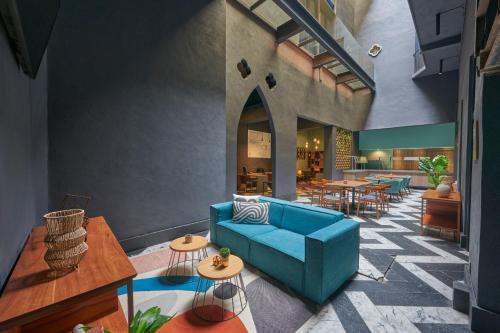 a living room with a blue couch and tables at City Centro by Marriott Ciudad de Mexico in Mexico City