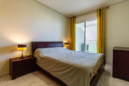a bedroom with a bed with a lamp and a window at Apartment VilaPark with pool, free parking, terrace, beach in Benidorm