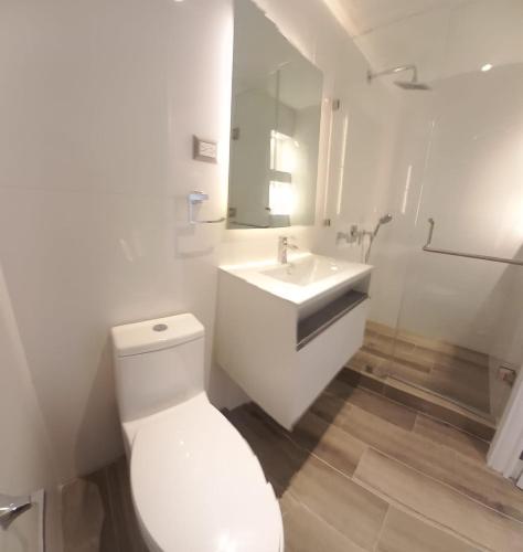 a white bathroom with a toilet and a sink at Apartamento 2 Habitaciones, Edificio Airali, Zona 10, Napoles in Guatemala