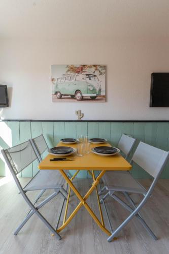 une table jaune avec des chaises et un tableau de camionnette sur le mur dans l'établissement Appartement avec parking - Futuroscope - 1 à 4 personnes, à Jaunay-Clan