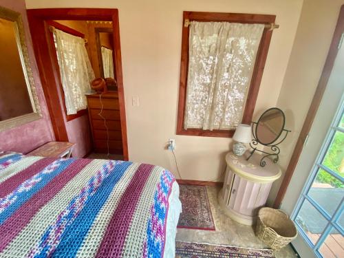 a bedroom with a bed and a mirror and a window at Artsy Cabin on Organic Farm in Naalehu
