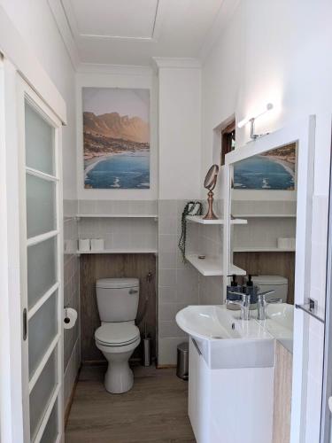 a white bathroom with a toilet and a sink at Above the Sea in Fish Hoek
