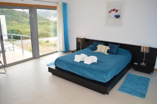 a bedroom with a bed with blue sheets and a balcony at Foz Ocean Retreat in Foz do Arelho