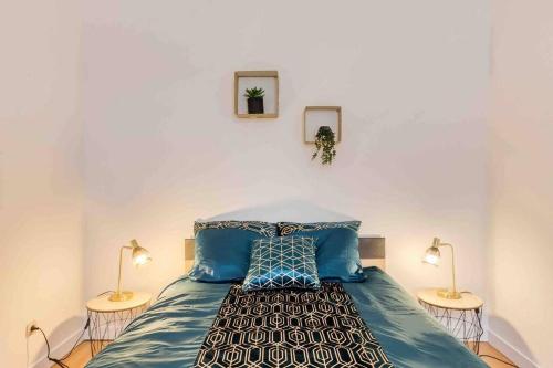 a bedroom with a bed with blue sheets and two lamps at Paris Gentilly appartement tout équipé - RER B in Gentilly