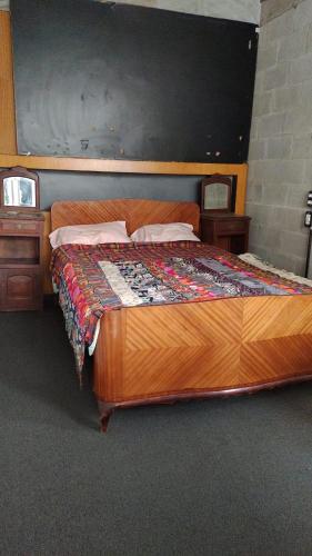 Cette chambre comprend un grand lit en bois et 2 tables. dans l'établissement departamento d City Bell, à City Bell
