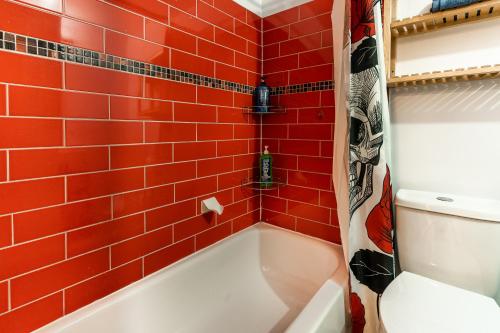 baño de azulejos rojos con bañera y aseo en Cozy 1 bedroom apartment - 107, en Montreal