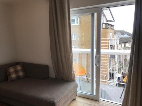 a living room with a couch and a sliding glass door at En-suite room with a superking size bed and balcony in London