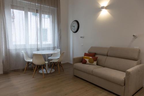 un soggiorno con divano, tavolo e orologio. di Alda nella piazzetta in centro a La Spezia