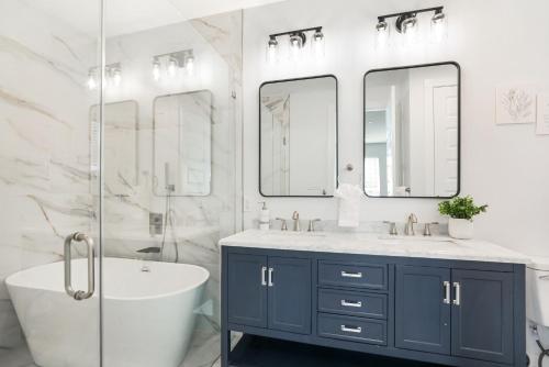 Un baño con bañera, lavabo y dos espejos. en New 3-Bed Luxury House, en Nueva Orleans