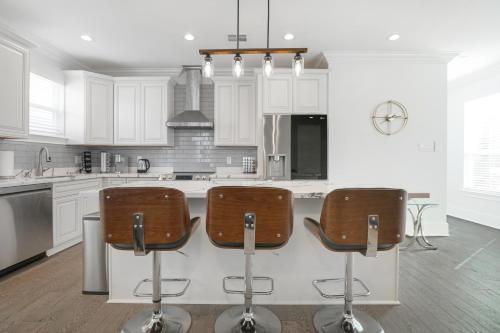 a kitchen with white cabinets and bar stools at New 3-Bed Luxury House in New Orleans