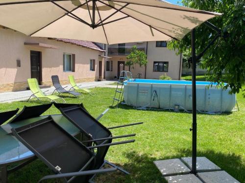 um guarda-sol num quintal com cadeiras e uma piscina em Lovely 1 bedroom flat in a 2 ground floor house em Craiova