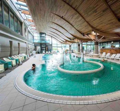 - une grande piscine dans un bâtiment avec des personnes dans l'établissement Le Perchoir du lac ~ Vue plongeante Lac & Montagne, à Tresserves