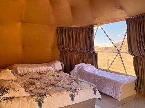 two beds in a room with a window at Wejdan Rum Luxury Camp in Wadi Rum