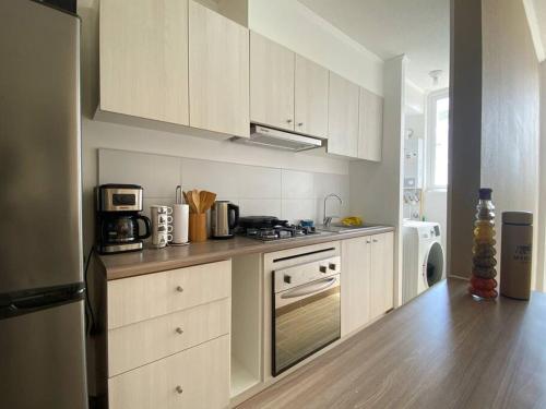 uma cozinha com armários brancos e um forno com placa de fogão em Depto nuevo con estacionamiento em Puerto Montt