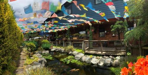 einen Garten mit einem Teich und ein Gebäude mit Flaggen in der Unterkunft Casa Azul Hostel in Puerto Varas