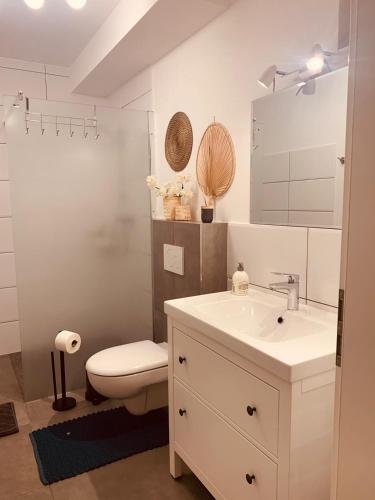 a white bathroom with a toilet and a sink at Apartment am Engelsblick - die Eifel direkt vor der Tür in Kreuzau