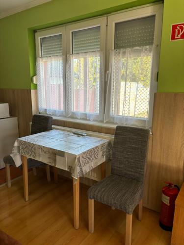 a dining room table with two chairs and a window at Horvath Vendeghaz in Hegyeshalom