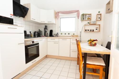 a kitchen with white cabinets and a table with chairs at Zentrale ruhige 3-Zimmer-Wohnung in Kassel