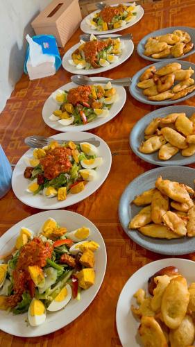 a wooden table with plates of food on it at Batur cottage in Kubupenlokan