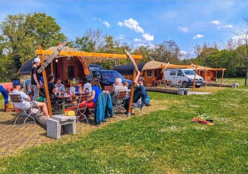 a group of people sitting at a table in front of a tent at Rheingau 524 Schlaffassdorf direkt am Rhein in Geisenheim