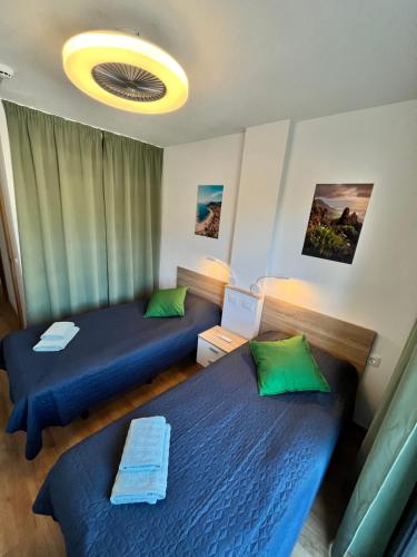 two beds in a room with blue sheets and green pillows at Family apartment “Tenerife with love!” in Arona