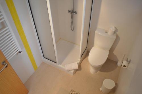 La salle de bains blanche est pourvue d'une douche et de toilettes. dans l'établissement Foz Ocean Retreat, à Foz do Arelho