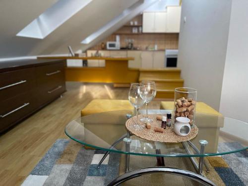 een woonkamer met een glazen tafel en wijnglazen bij Apartman Centar E&A in Tuzla