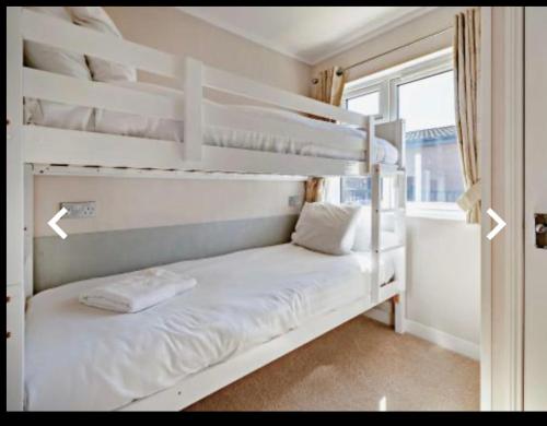 two white bunk beds in a room with a window at Ness Lodge in Little Habton