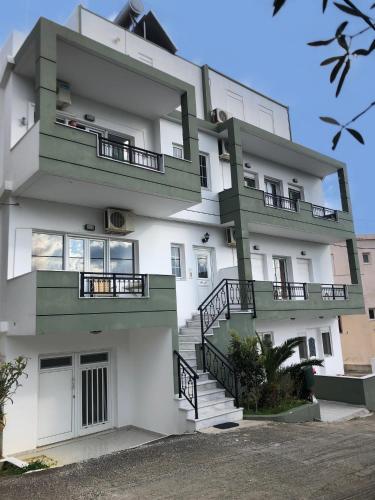 a large white building with green balconies and stairs at Blue Sky Apartments I in Makry Gialos