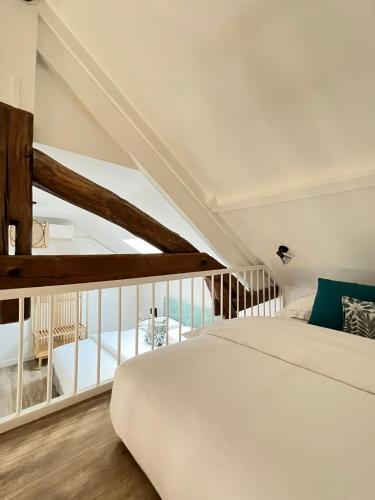 a bedroom with a white bed and a balcony at Le Gite de Florian in Chablis