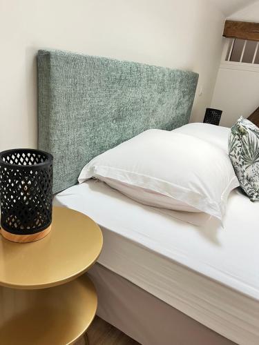 a bed with a green headboard next to a table at Le Ptit Gite de Chablis - Maison avec Cour en Centre-Ville in Chablis