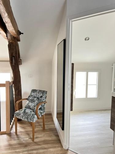 a living room with a chair and a mirror at Le Ptit Gite de Chablis - Maison avec Cour en Centre-Ville in Chablis