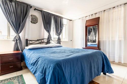 um quarto com uma cama com lençóis e cortinas azuis em Aparta estudio en la capital colombiana em Bogotá