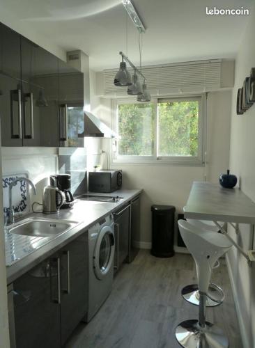 une cuisine avec un évier et une machine à laver dans l'établissement Appartement de standing 60m de la plage, à La Baule