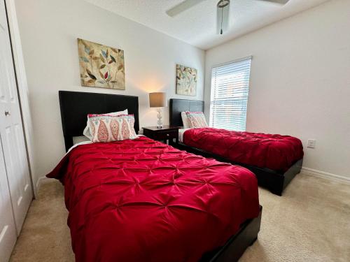 a bedroom with two beds with red sheets and a window at Villa with Pool in Gated 18-hole Golf Community with self-checkin after 4pm in Davenport