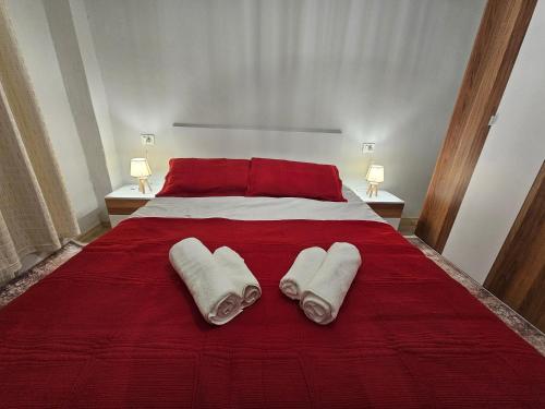 a bedroom with a red bed with two towels on it at Library Apartment by Bohem Rentals in Durrës