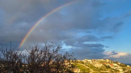 a rainbow in the sky over a city at Blessed view in Keratea