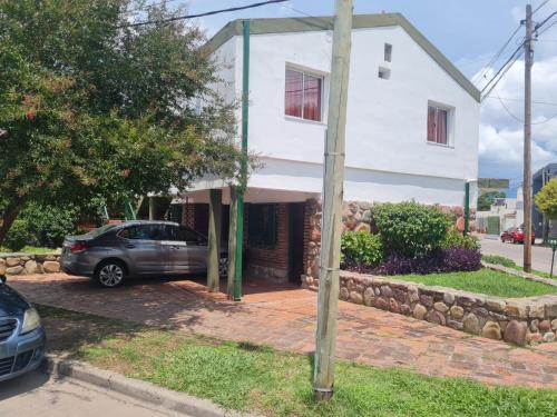 a white house with a car parked in the driveway at Amelí Alojamiento in Salta