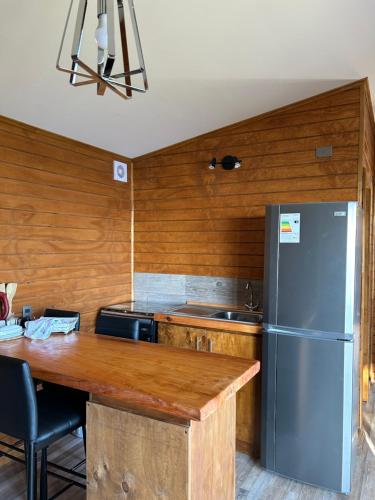 a kitchen with a stainless steel refrigerator and a table at Cabañas Lakü in Ñilque