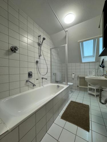 een witte badkamer met een bad en een wastafel bij Fewo BOHO 110 qm mit Bergblick 3 min Bahnhof in Laufen