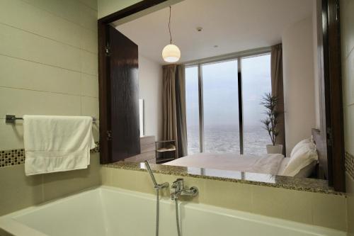 La salle de bains est pourvue d'une baignoire et d'une fenêtre avec un lit. dans l'établissement private Suite by Golden Hospitality 98, à Riyad