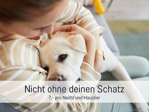 a woman is holding a dog in her lap at Ferienhaus Töpferhaus - strandnah, haustierfreundlich, optimal für Workation, Kaminofen, Garten, für Paare und Alleinreisende in Steinberg