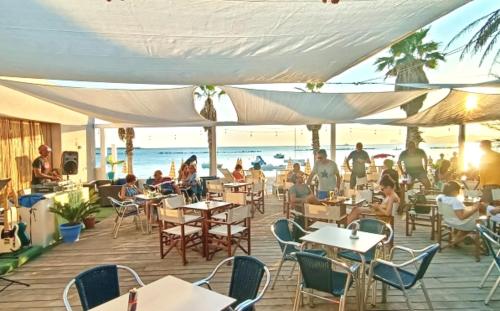 a group of people sitting at tables on the beach at Lido Di Alghero Rooms on the Beach in Alghero