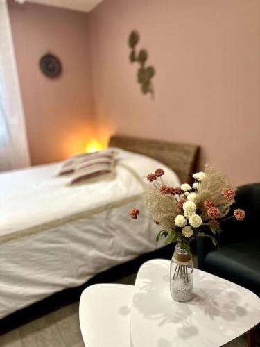 une chambre avec un lit et un vase de fleurs sur une table dans l'établissement Studio Millésime, à Nogent-lʼArtaud