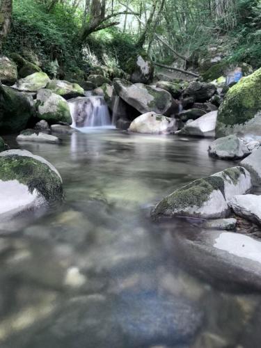 a stream of water with rocks and a waterfall at chambre au calme in Saint-Jean-dʼArvey