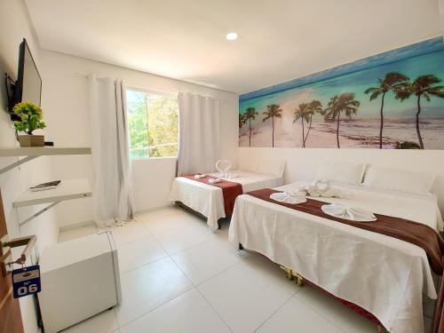 um quarto com duas camas e um quadro na parede em Encantos de Maragogi em Maragogi
