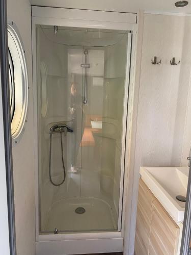 une douche avec une porte vitrée dans une salle de bain dans l'établissement Plouescat, à Plouescat