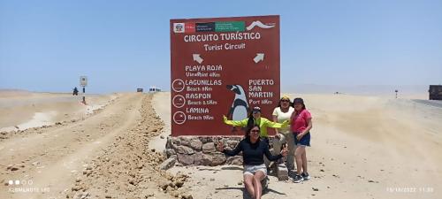 a group of people standing next to a sign in the desert at ALOJAMIENTO ISLA BLANCA in Paracas