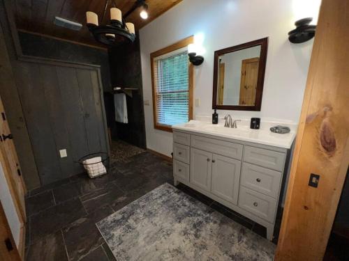 uma casa de banho com um lavatório e um espelho em Nantahala Nook, cabin w/hot tub,game room, & wifi em Bryson City