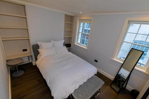 um quarto com uma cama com lençóis brancos e prateleiras em Entire Knightsbridge Mews House em Londres